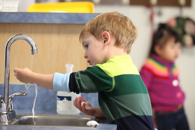 Little boy washing his hands at sink
